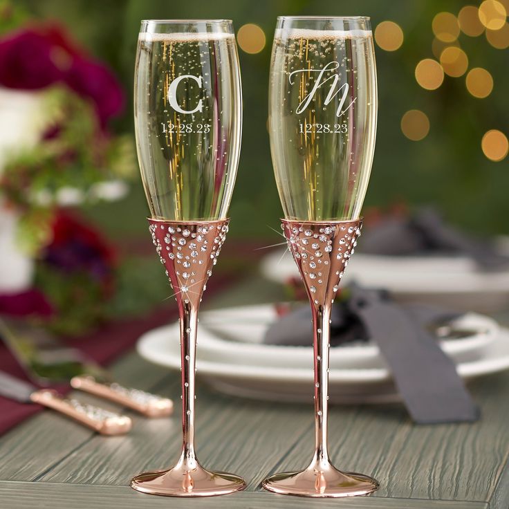 two champagne flutes sitting on top of a table next to plates and utensils