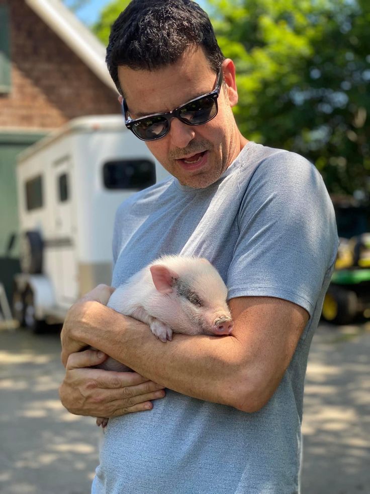 a man holding a small white animal in his arms