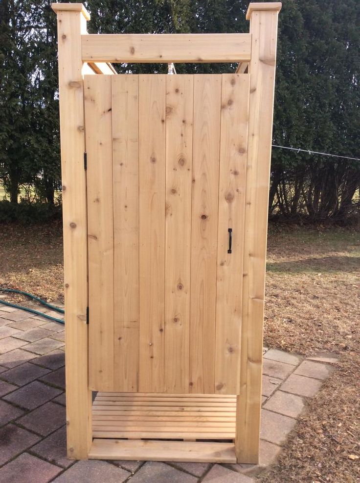 a wooden bench sitting in front of a wooden gate on top of a brick walkway