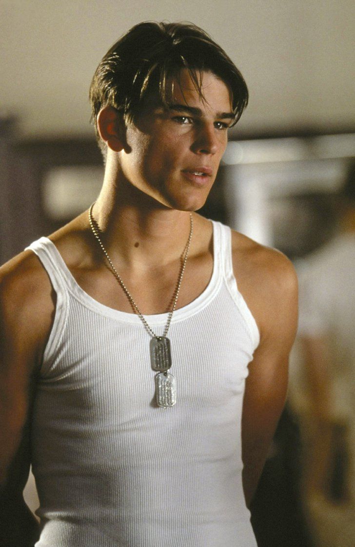 a young man wearing a white tank top with a necklace on it's neck