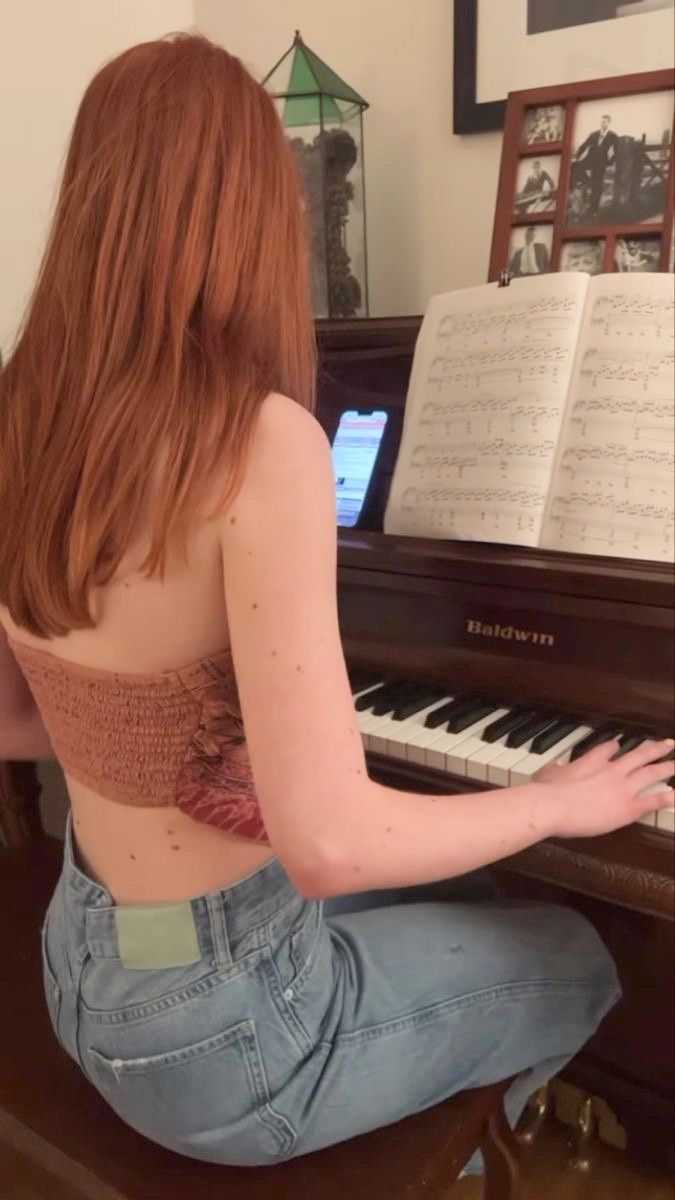 a woman sitting on the floor playing a piano with music sheets in the back ground