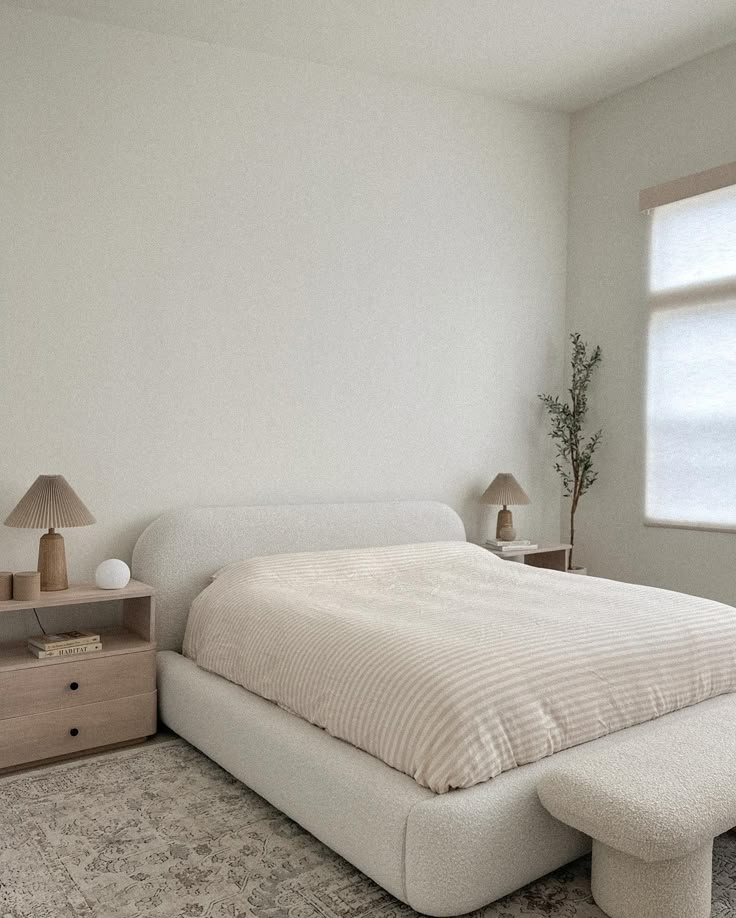 a white bed sitting next to a window in a bedroom on top of a rug