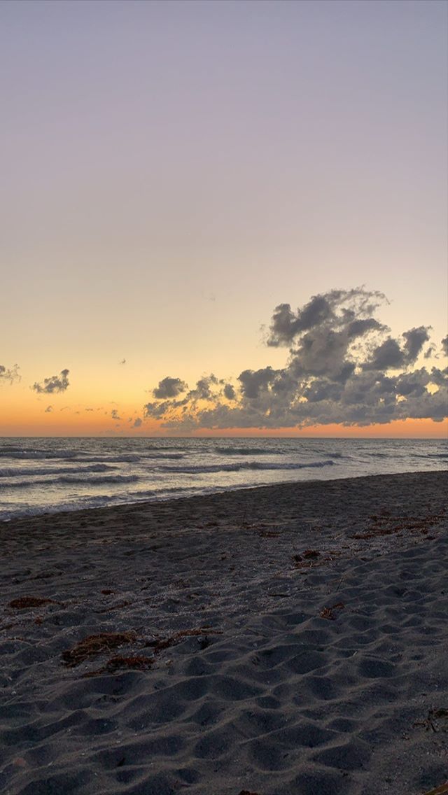 the sun is setting at the beach with waves coming in