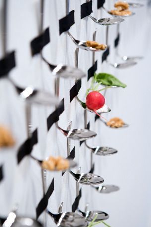 there are many spoons with food on them hanging from the side of a wall