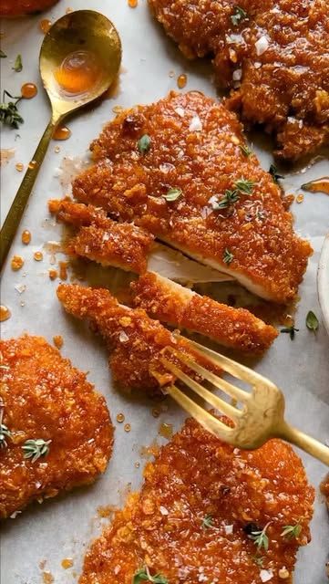 chicken parmesan on a sheet of parchment paper with golden spoons next to it