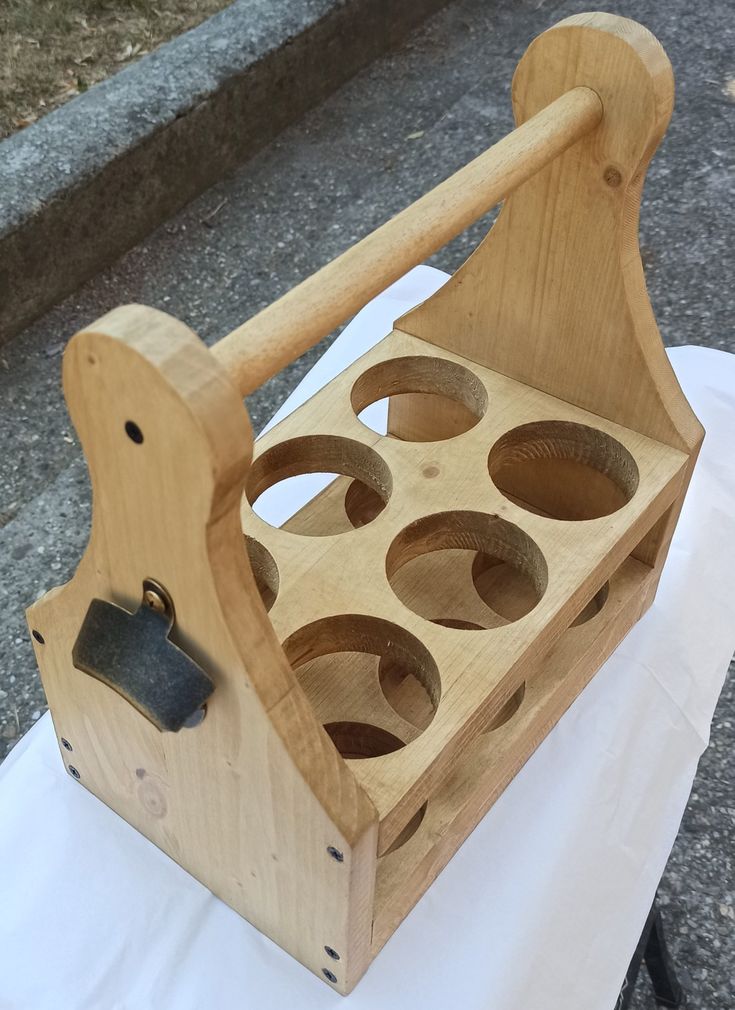 a wooden caddy with holes in it on a white table cloth next to a sidewalk