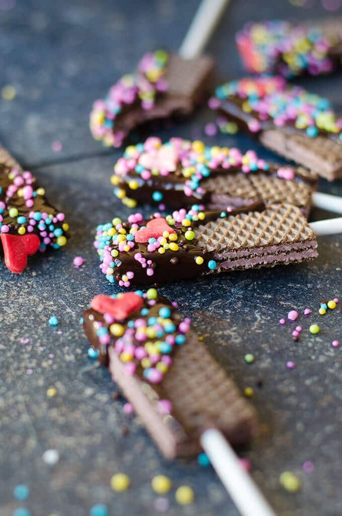 chocolate covered waffles with sprinkles and hearts on them sitting on the ground