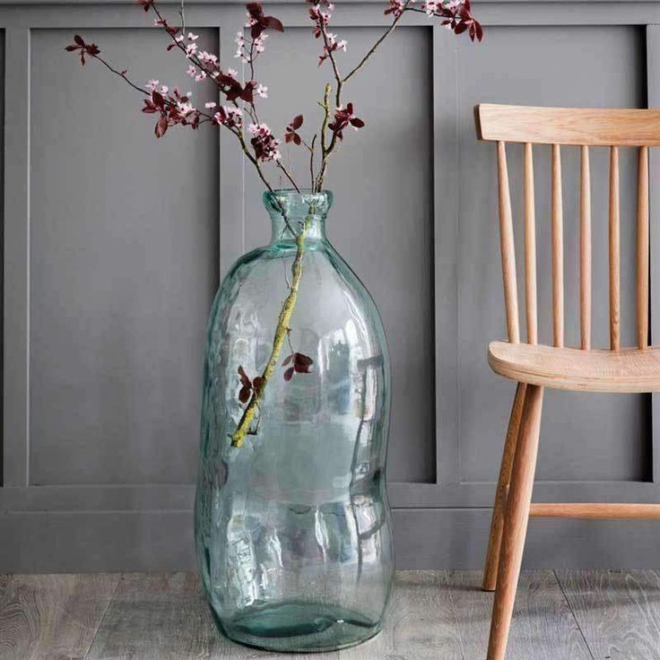 a vase filled with flowers sitting on top of a wooden floor next to a chair