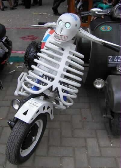 a motorcycle with a skeleton on the front and back tire is parked near other motor scooters