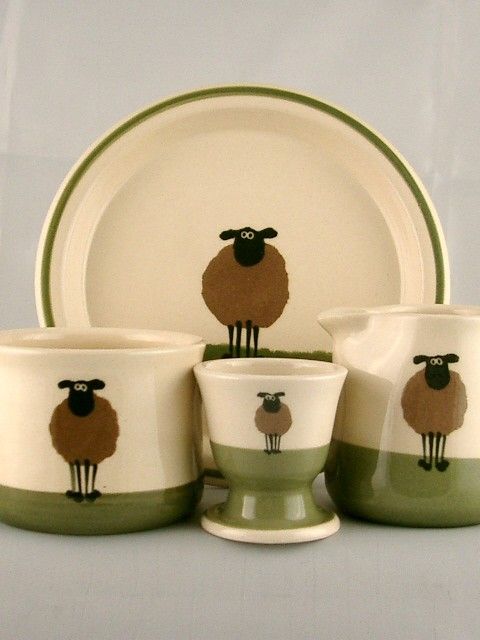 a set of four dishes with sheep on the front and side, one is green