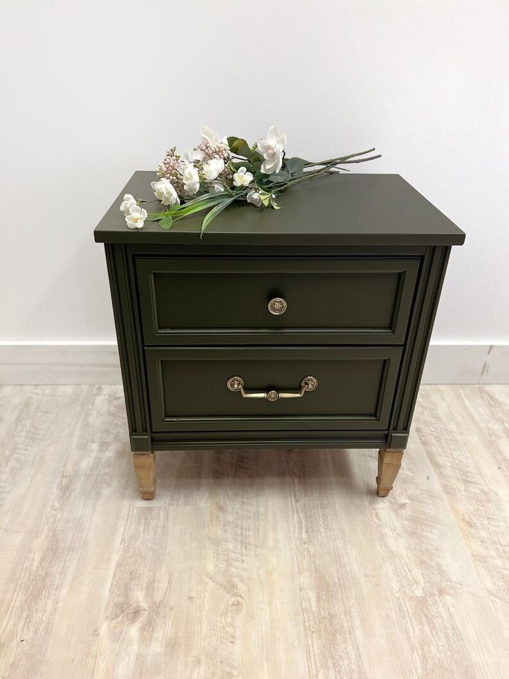 two drawers with flowers on top of them in front of a white wall and wood floor