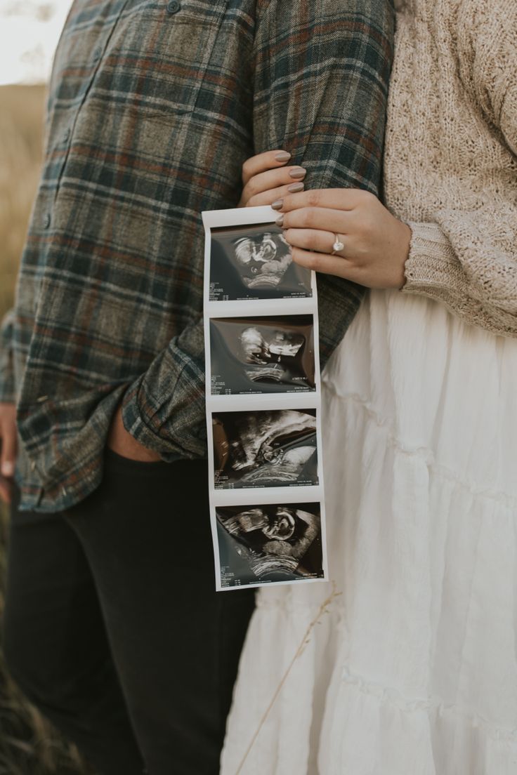 a man and woman standing next to each other holding an envelope with pictures on it