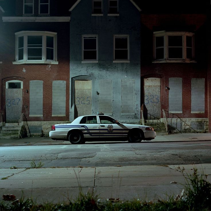 a police car is parked in front of an abandoned building on the street at night