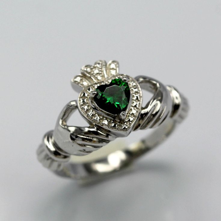 a ring with a heart shaped green stone in the center