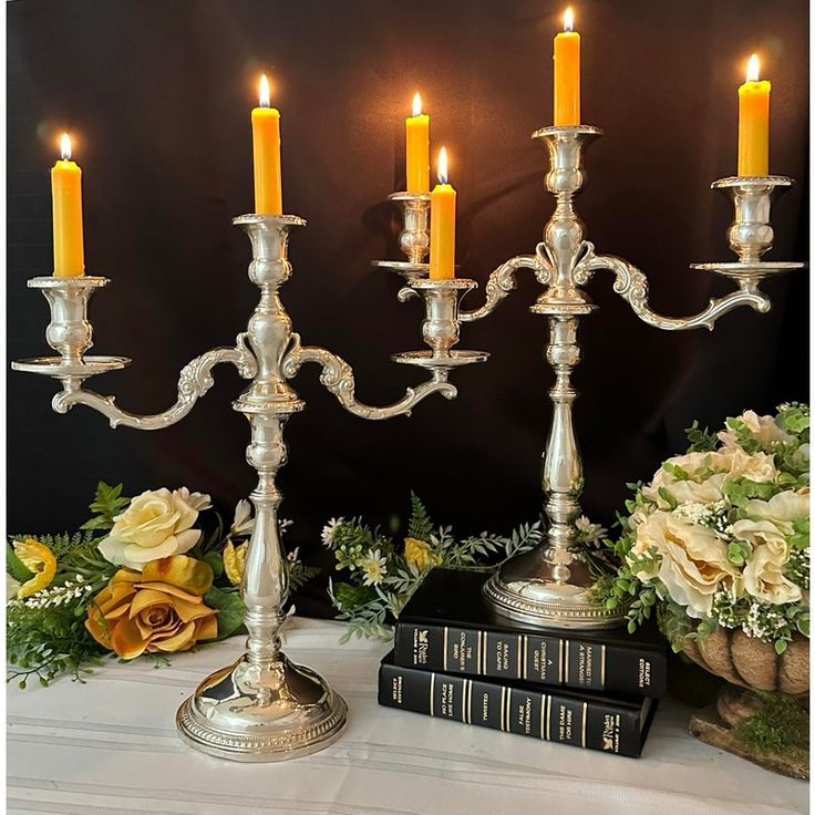 four candles are lit on a table with flowers