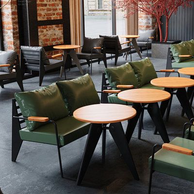 tables and chairs are lined up in an open area with brick walls, windows, and green cushions