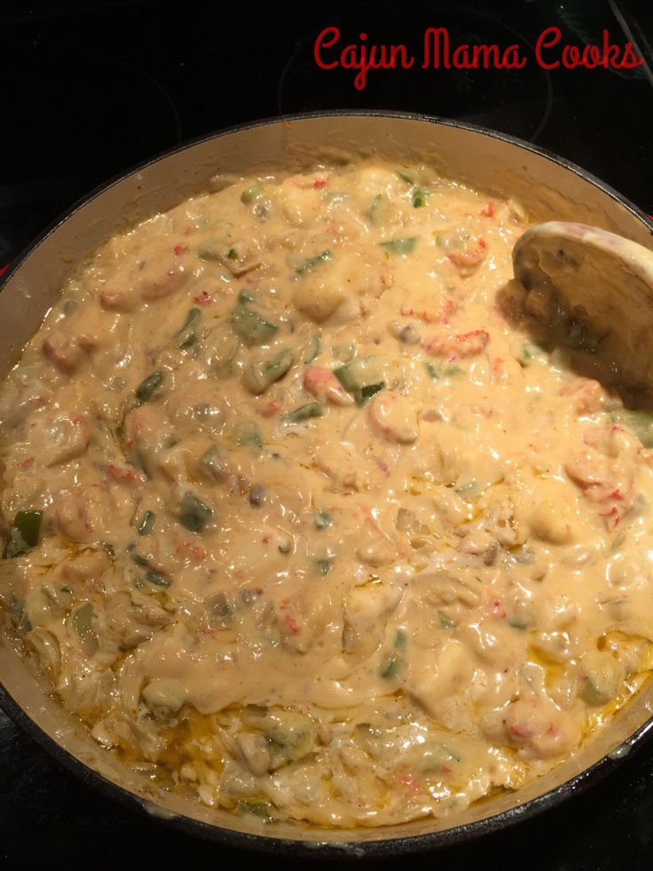 a skillet filled with food sitting on top of a stove next to a wooden spoon