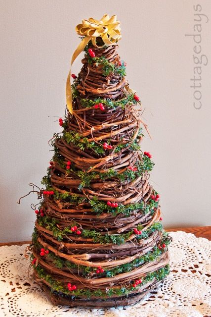 a christmas tree made out of branches and twigs on a doily table with a gold bow