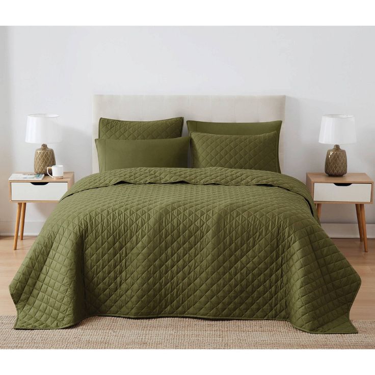 a bed with green bedspread and pillows