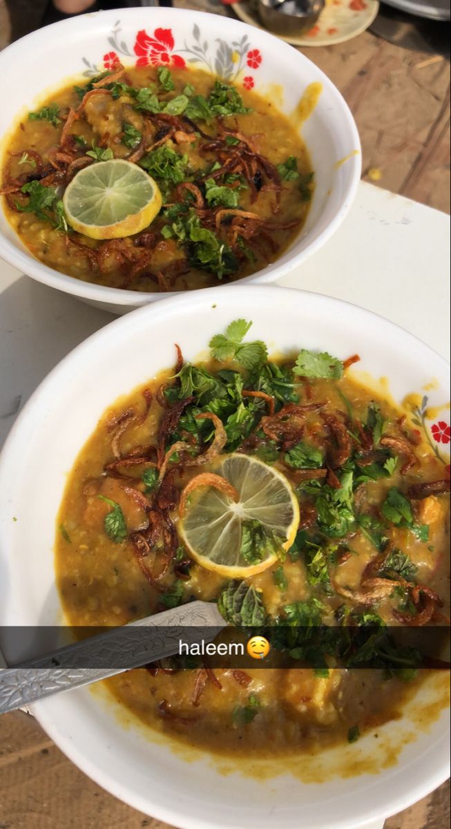 two white bowls filled with soup and garnished with limes on the side