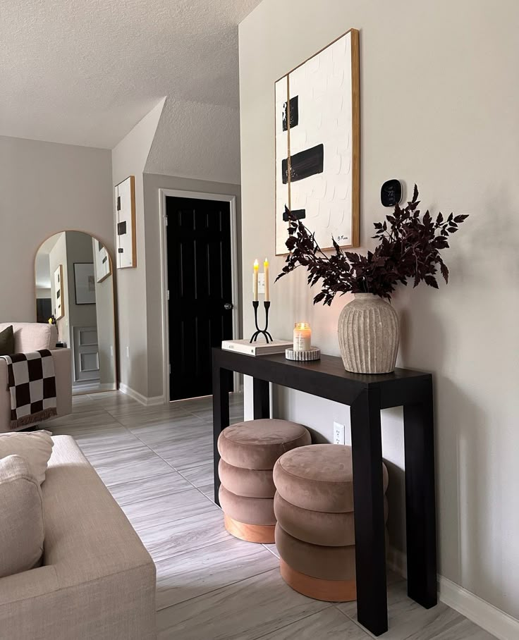 a living room filled with furniture and a vase on top of a wooden table in front of a mirror