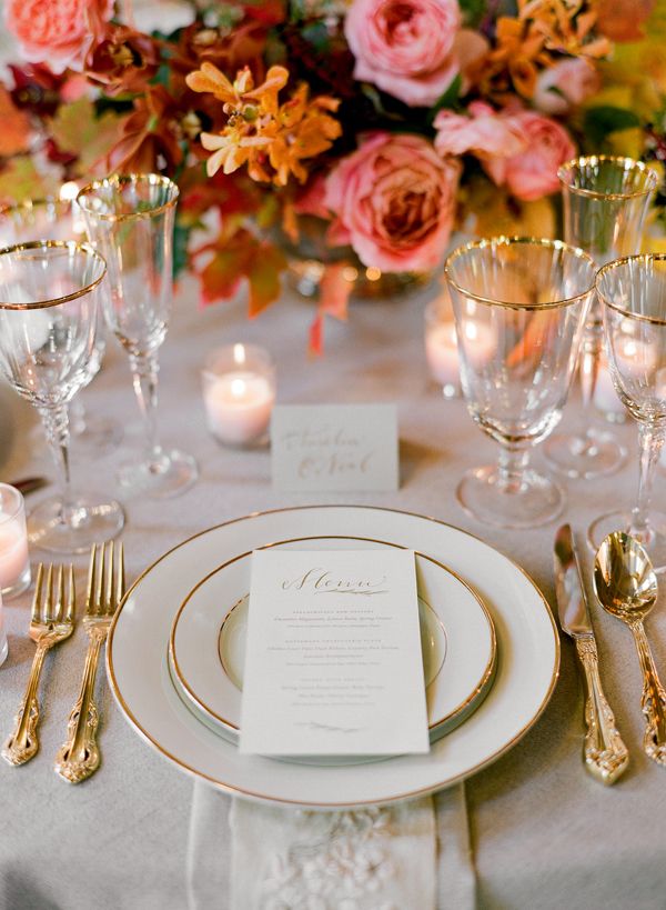 an image of a table setting with flowers in the background and place settings on it