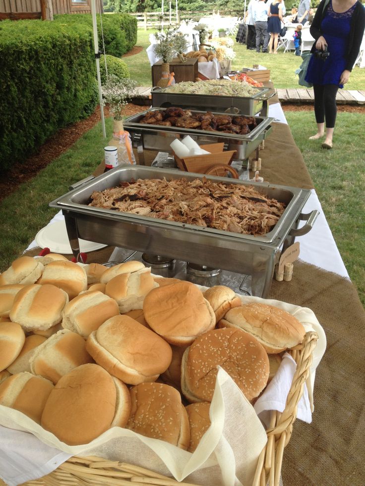 several trays of food sitting on top of a table in front of some people