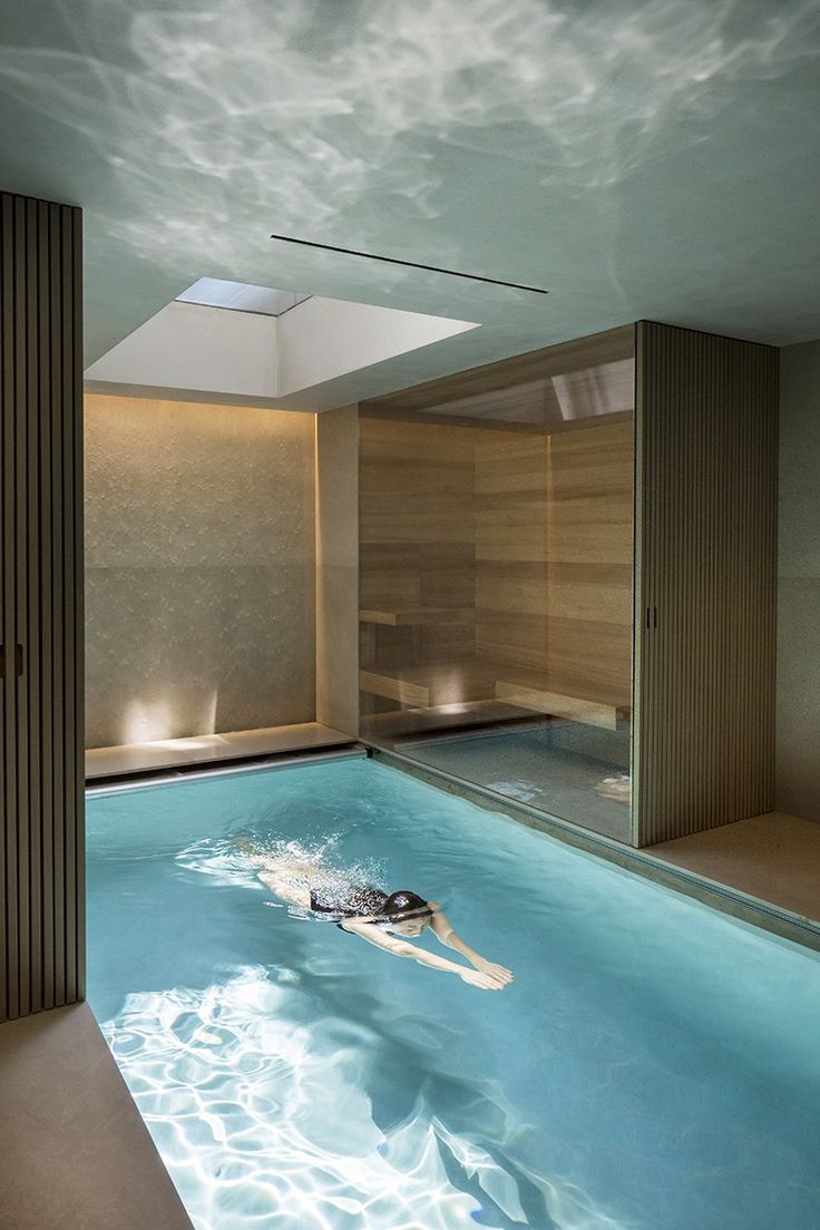 an indoor swimming pool with a skylight above it and a person floating in the water