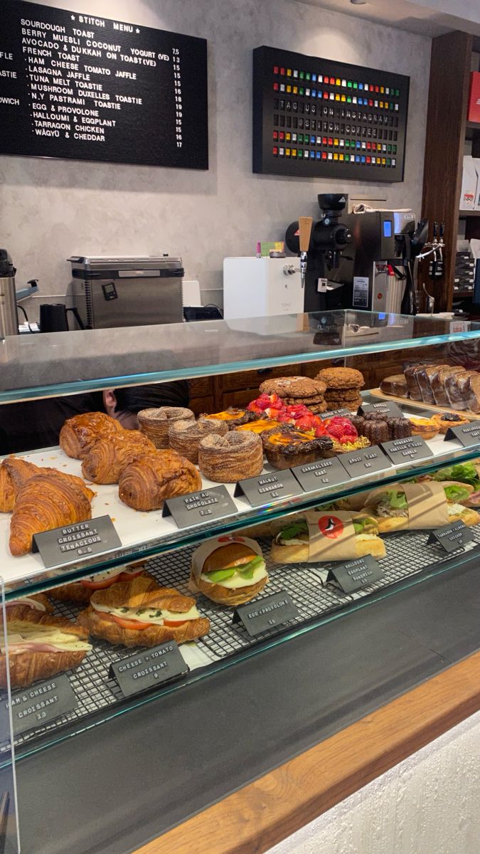 a display case filled with lots of different types of sandwiches and pastries in front of a coffee shop