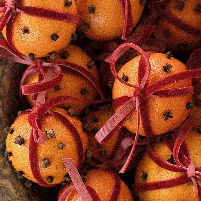 several oranges tied with red ribbon and chocolate chips in a bowl on top of a table