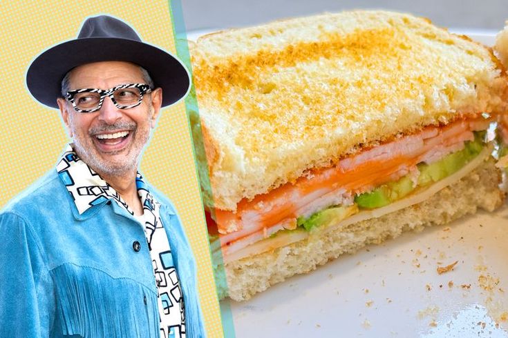 a man in a hat and glasses is next to a cut in half sandwich on a plate