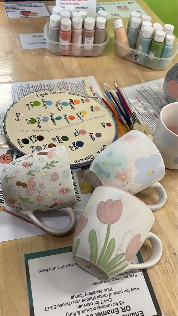 there are many cups and mugs on the table with crafting supplies around them