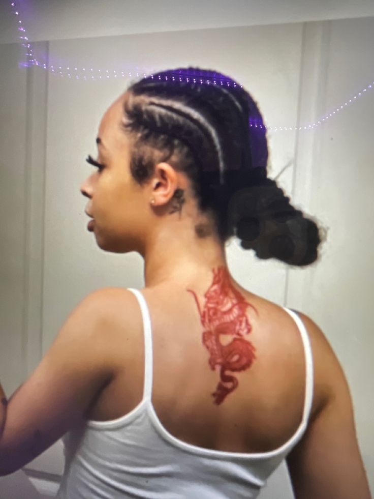 a woman with a dragon tattoo on her upper back shoulder and neck is looking in the mirror