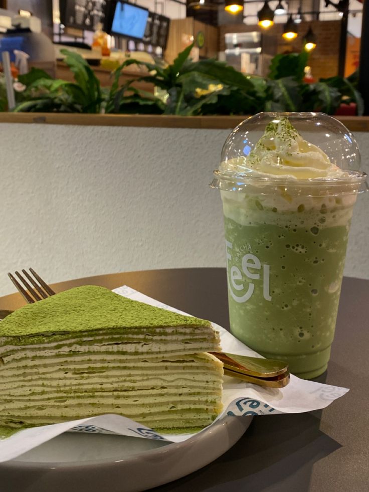 a stack of green crepes next to a drink on a table in a restaurant