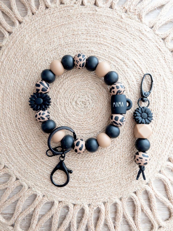 a bracelet with black, white and brown beads is on a round rug next to a pair of scissors