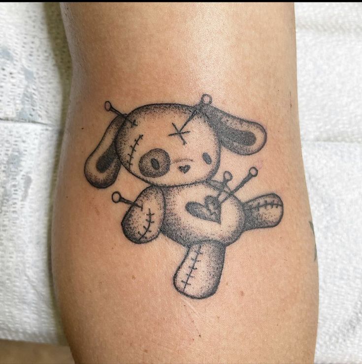 a tattoo on the leg of a person with a teddy bear and crossbones