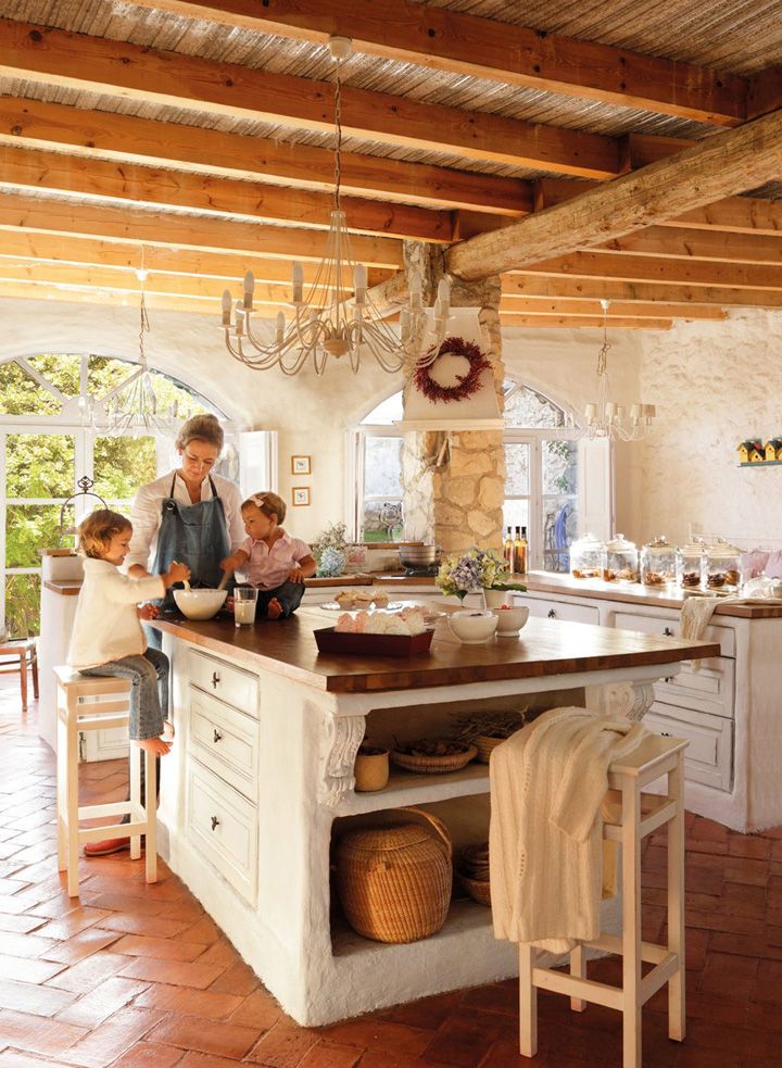 a woman and two children standing in a kitchen with an island counter top that has pots on it