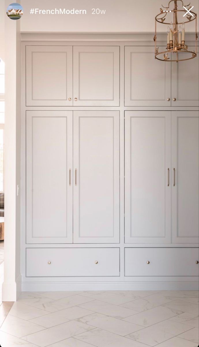 an empty room with white cabinets and chandelier