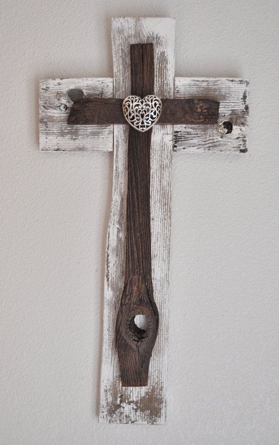 a wooden cross hanging on the wall with a heart shaped object in it's center