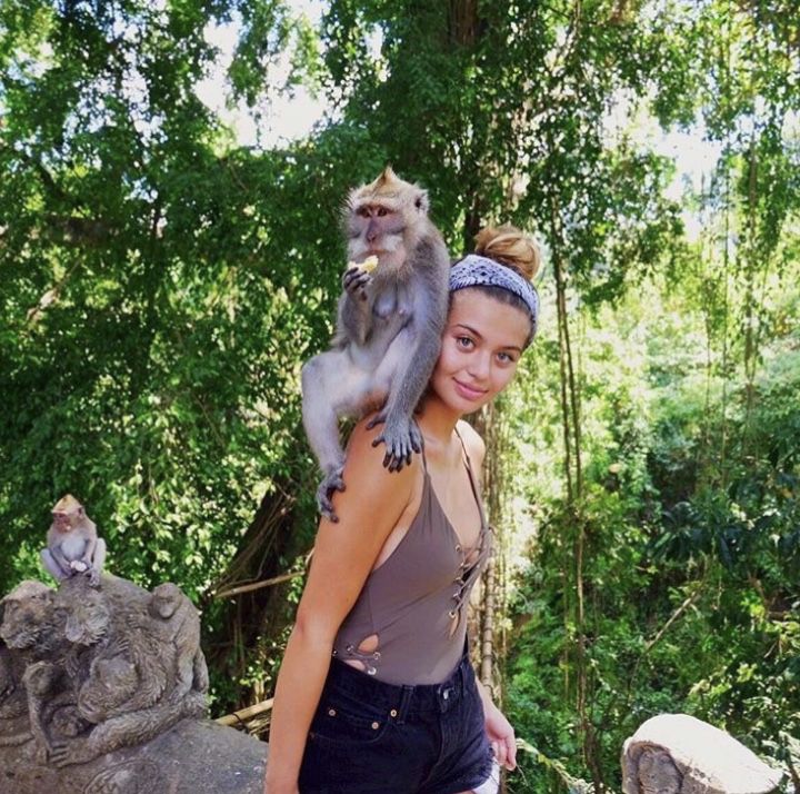 a woman holding a monkey on her shoulders