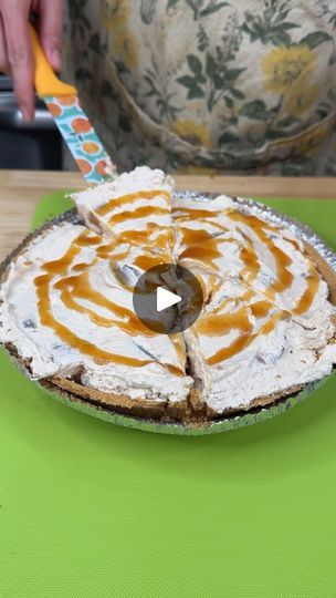 a person cutting into a pie on top of a green table