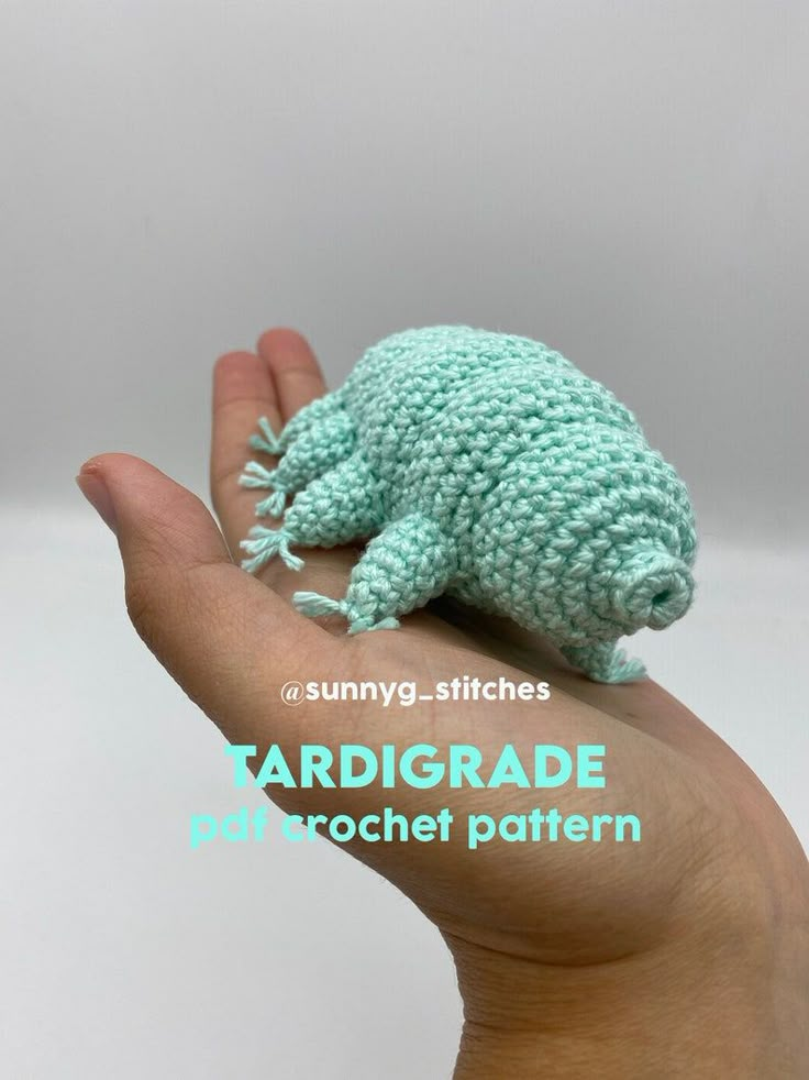 a hand is holding a small crocheted frog on it's palm with the caption tardigrade microcrochet pattern