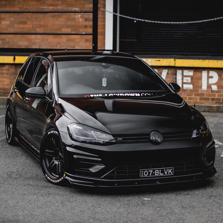 a black car parked in front of a brick building