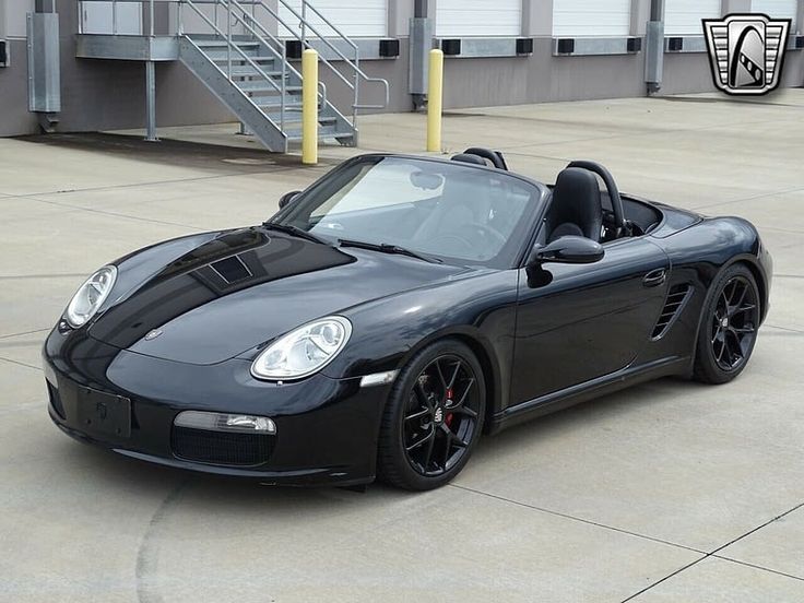 a black porsche sports car parked in front of a building with stairs leading up to it