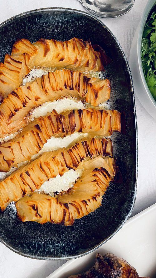 some food that is in a pan on a table with other plates and utensils