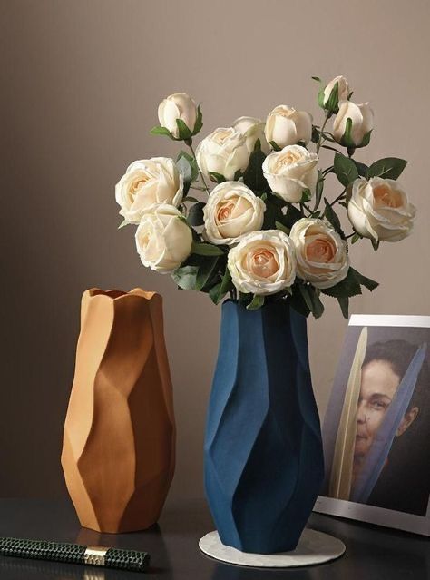 two vases with white roses in them on a table next to an empty photo