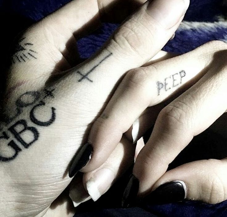 two hands with black and white tattoos on them, one has the word pee written on it