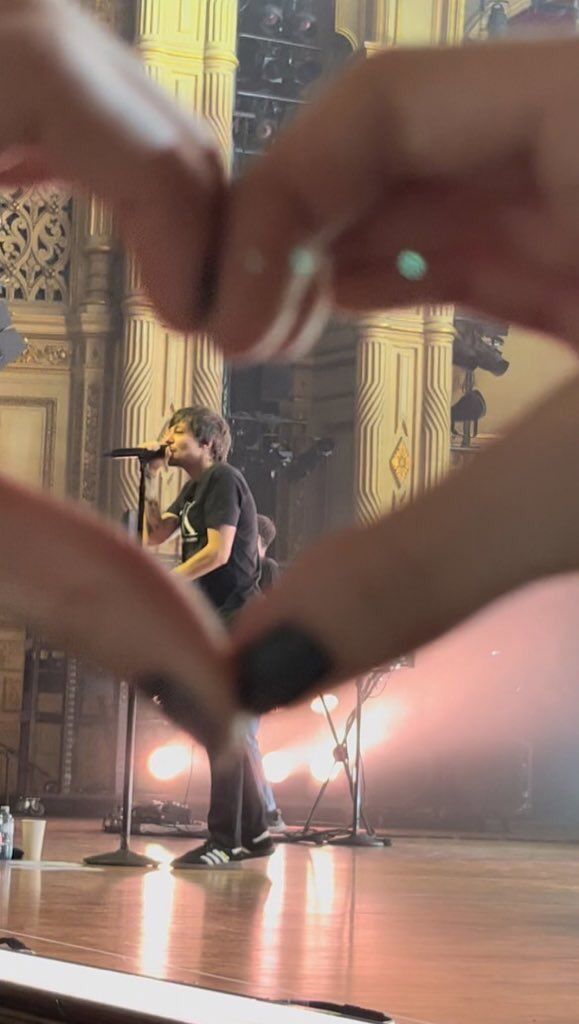 two hands reaching out to each other over a stage with microphones and lights in the background