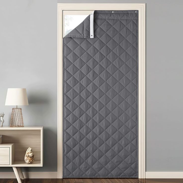 an open door with a grey quilted cover on it and a lamp next to it