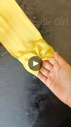 a hand is holding a yellow cloth with a bow on it's end,